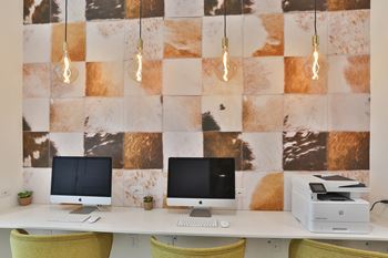 Two computer monitors on a desk with a wallpapered background.